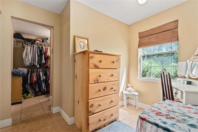 tiled bedroom with a spacious closet and a closet