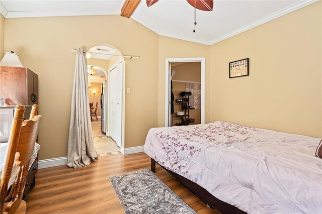 bedroom with lofted ceiling with beams, ornamental molding, hardwood / wood-style floors, and a closet