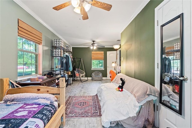 bedroom featuring ornamental molding, multiple windows, and light wood-type flooring