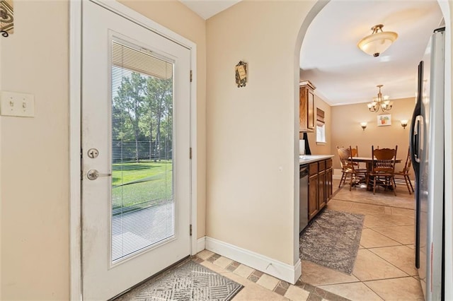 doorway to outside with an inviting chandelier, ornamental molding, and light tile patterned flooring