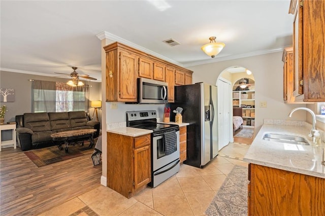 kitchen with ornamental molding, appliances with stainless steel finishes, sink, and light tile patterned floors