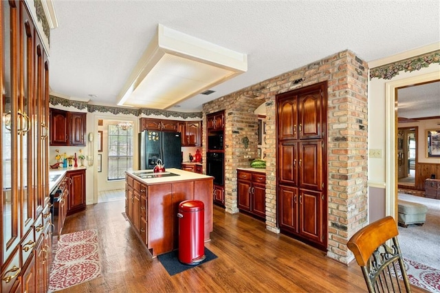 3425 Poe Rd S, Chunchula, AL 36521 - kitchen with black appliances, dark wood-style flooring, an island with sink, healthy amount of natural light, and a textured ceiling
