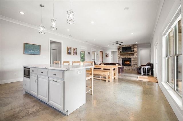 11531 Schmidt Ln S, Mobile, AL 36695 - kitchen featuring stainless steel microwave, a brick fireplace, a kitchen island, finished concrete flooring, and recessed lighting