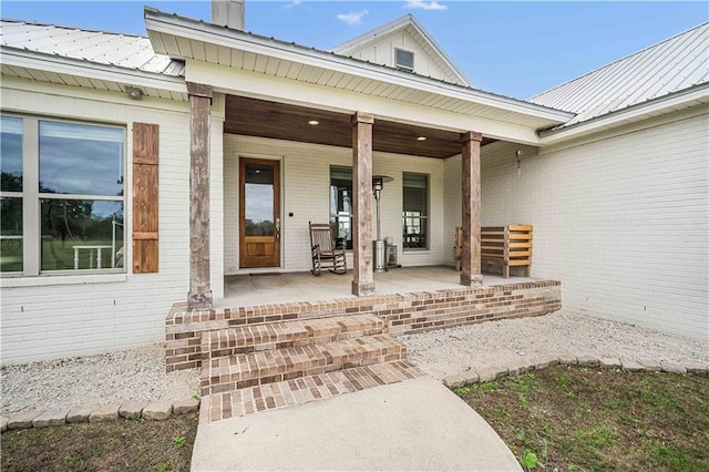 11531 Schmidt Ln S, Mobile, AL 36695 - view of exterior entry with a porch, brick siding, a chimney, and a metal roof