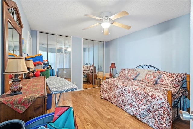 bedroom with a ceiling fan, wood finished floors, two closets, and a textured ceiling