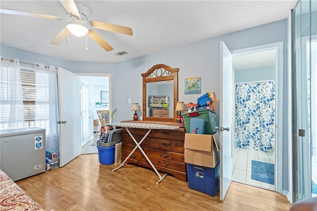 bedroom featuring white refrigerator, visible vents, a textured ceiling, and light wood-style flooring