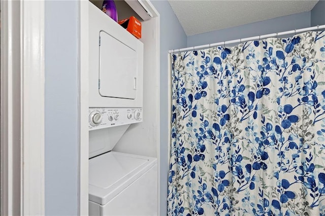 laundry room with stacked washer / drying machine, a textured ceiling, and laundry area