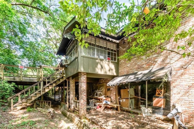 rear view of property featuring brick siding, a deck, and stairs