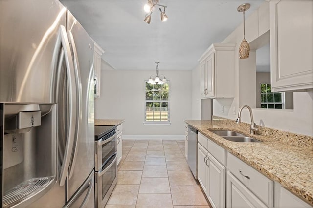 kitchen with sink, hanging light fixtures, light tile patterned floors, white cabinetry, and stainless steel appliances