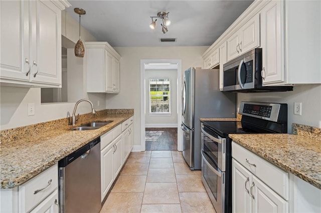 kitchen featuring white cabinetry, sink, stainless steel appliances, decorative light fixtures, and light tile patterned flooring