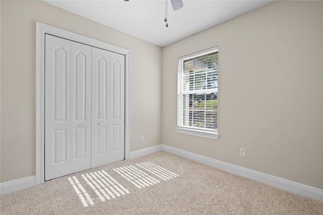 unfurnished bedroom featuring ceiling fan, light colored carpet, and a closet