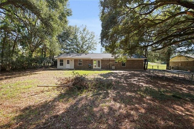 rear view of property with a lawn and a trampoline