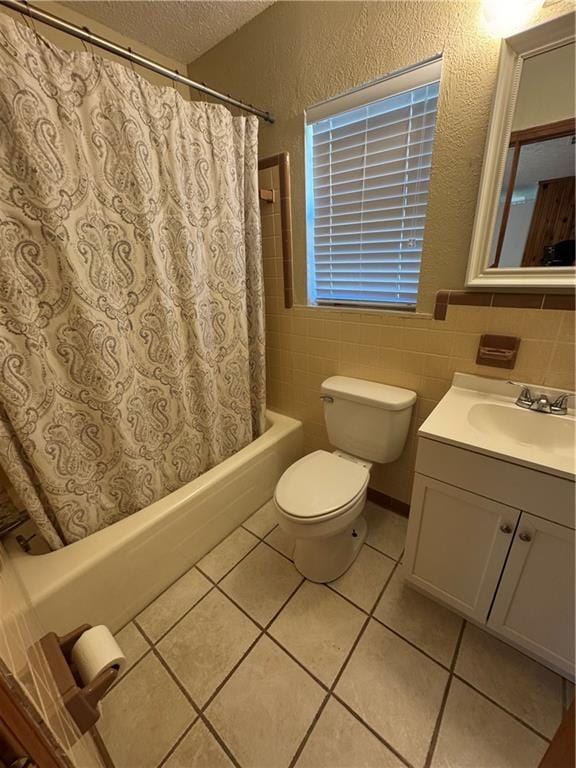 bathroom featuring tile walls, vanity, a textured ceiling, tile patterned floors, and toilet