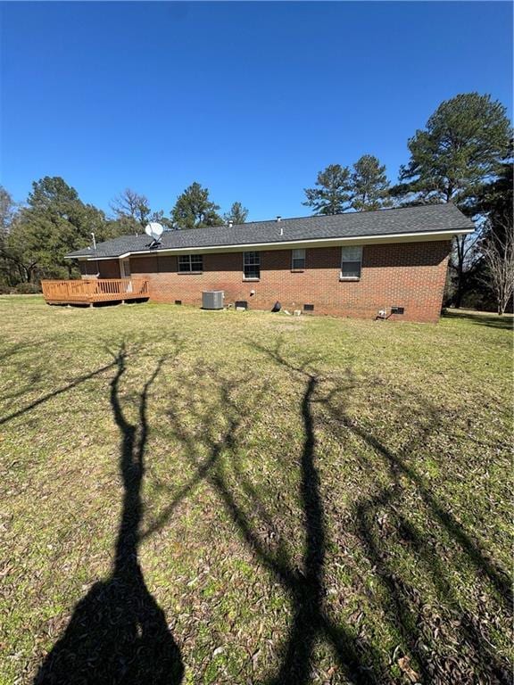 rear view of property with cooling unit, a yard, and a deck