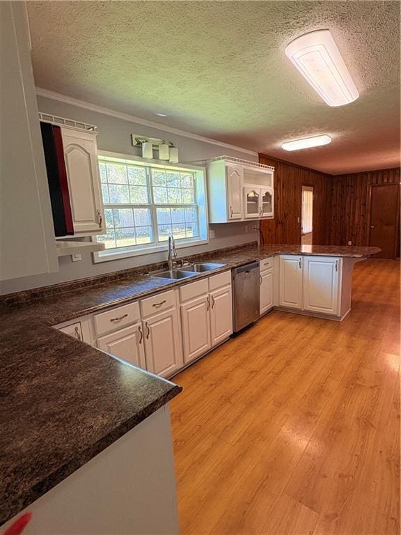 kitchen with sink, white cabinetry, light hardwood / wood-style flooring, stainless steel dishwasher, and kitchen peninsula