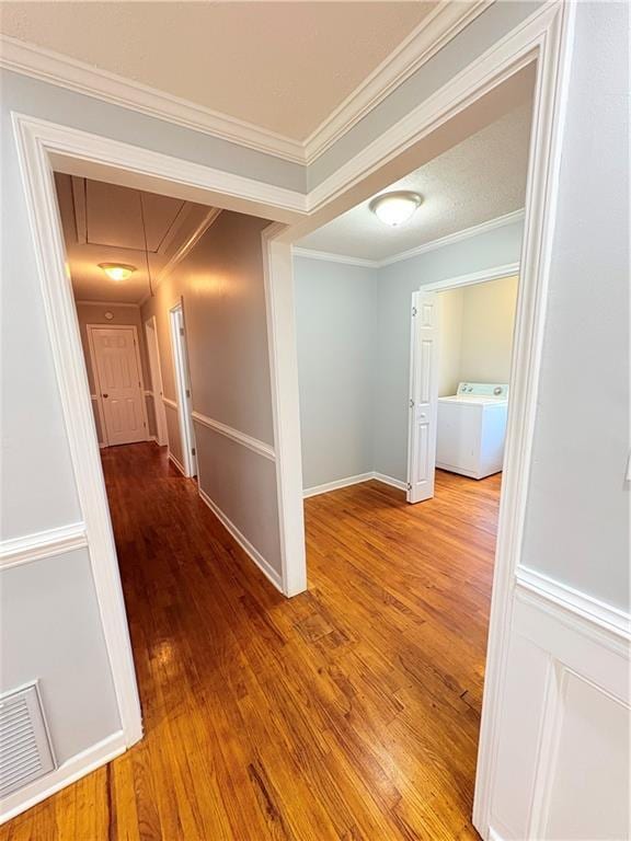 hallway featuring washer / clothes dryer, crown molding, and hardwood / wood-style flooring