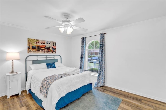 bedroom featuring wood finished floors, crown molding, and baseboards