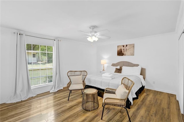 bedroom with wood finished floors, a ceiling fan, and baseboards