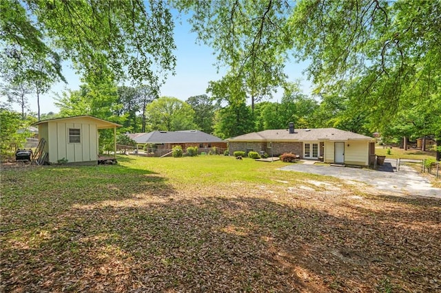 view of yard with fence, a storage shed, a patio area, an outbuilding, and french doors