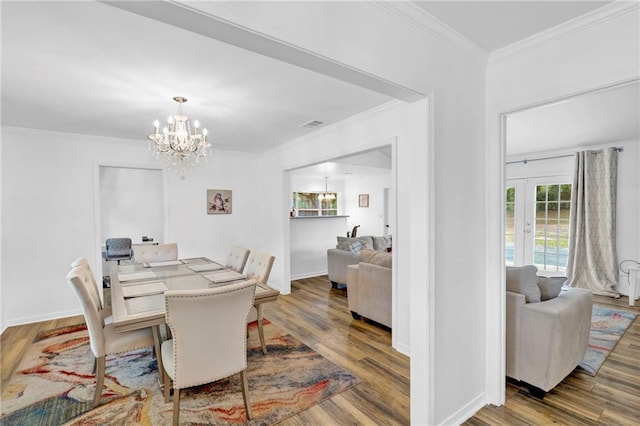 dining area with french doors, wood finished floors, a chandelier, and crown molding