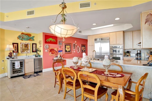 kitchen featuring stainless steel appliances, wine cooler, pendant lighting, light tile patterned floors, and light brown cabinetry