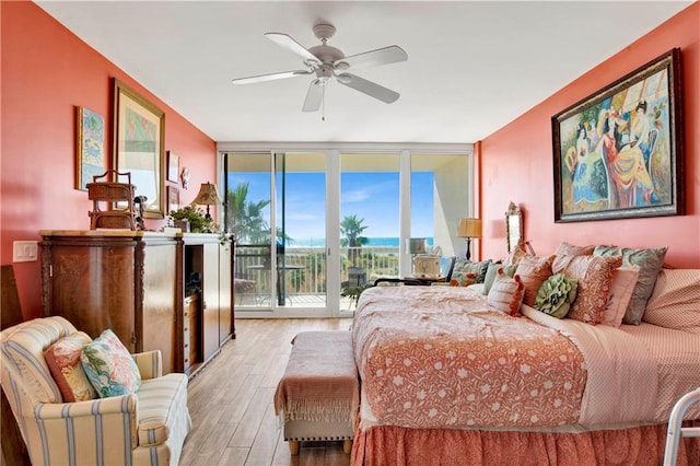 bedroom featuring ceiling fan, access to outside, light wood-type flooring, and floor to ceiling windows