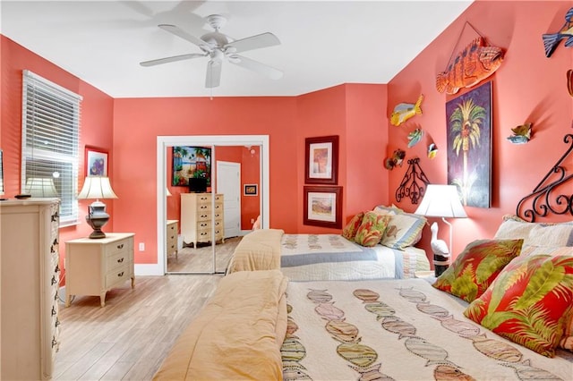 bedroom with a closet, light hardwood / wood-style floors, and ceiling fan