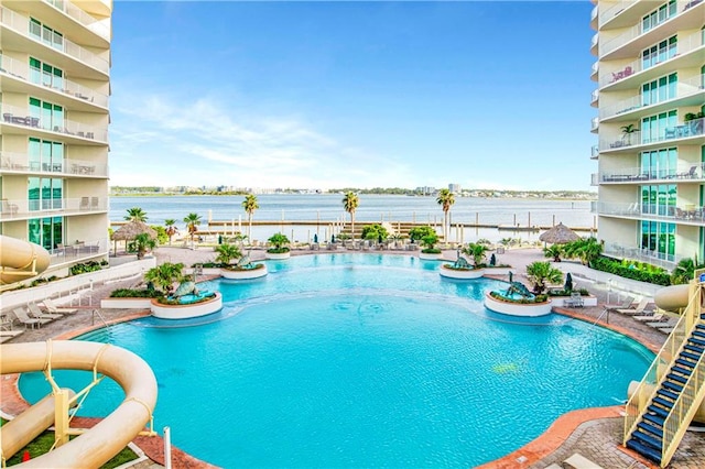 view of pool featuring a water view, a water slide, and a patio area