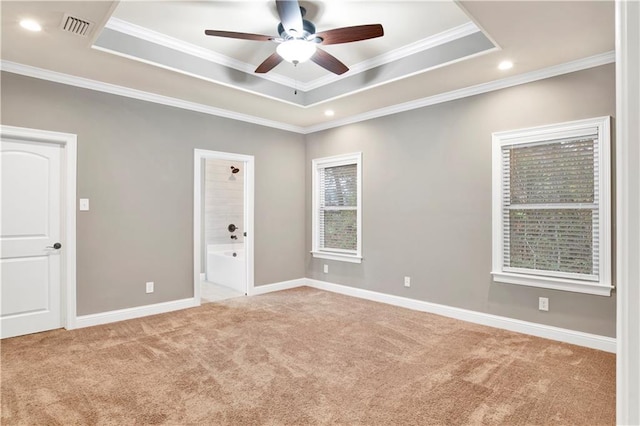 carpeted empty room with a raised ceiling, ornamental molding, and ceiling fan