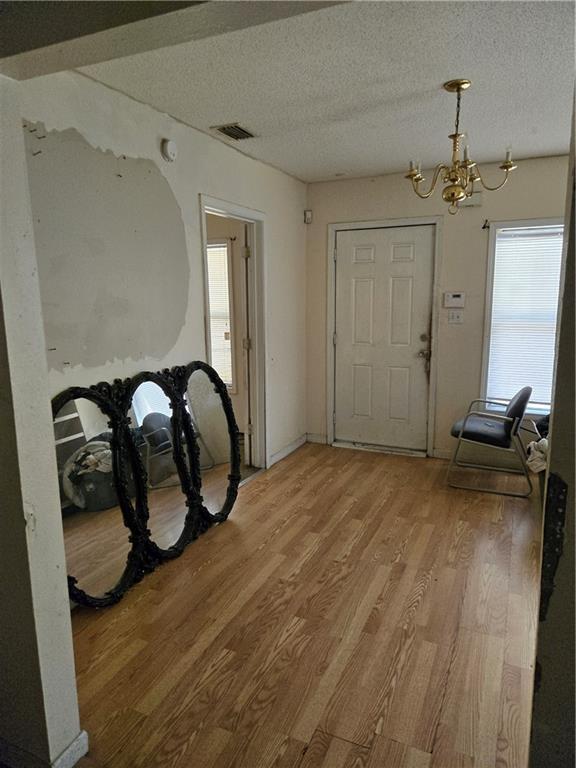 724 Half Ave, Mobile, AL 36610 - entryway featuring a textured ceiling, visible vents, light wood-type flooring, and a chandelier