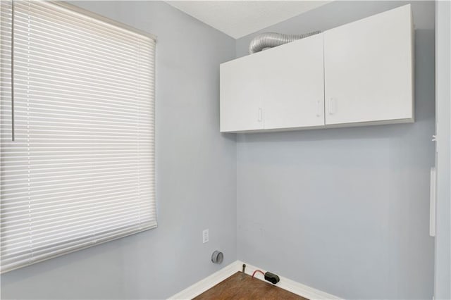 laundry area with baseboards, cabinet space, and wood finished floors