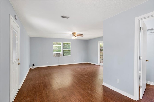 empty room featuring baseboards, dark wood-style flooring, visible vents, and a ceiling fan