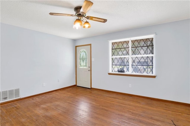 entryway featuring a textured ceiling, visible vents, hardwood / wood-style flooring, baseboards, and a ceiling fan