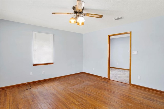 empty room with a textured ceiling, visible vents, baseboards, ceiling fan, and hardwood / wood-style floors
