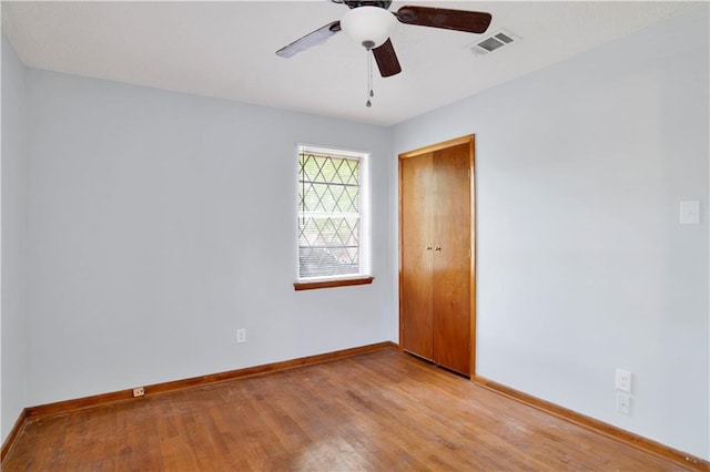 unfurnished room with ceiling fan, baseboards, light wood finished floors, and visible vents