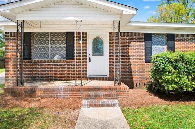 doorway to property with brick siding and a porch