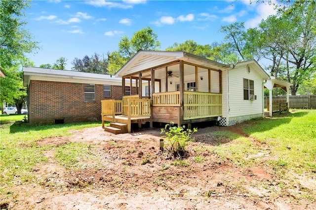 back of property with cooling unit, a deck, fence, brick siding, and a lawn