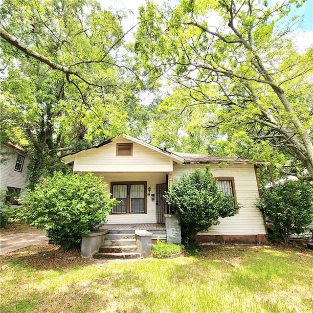 view of front of home with covered porch and a front lawn