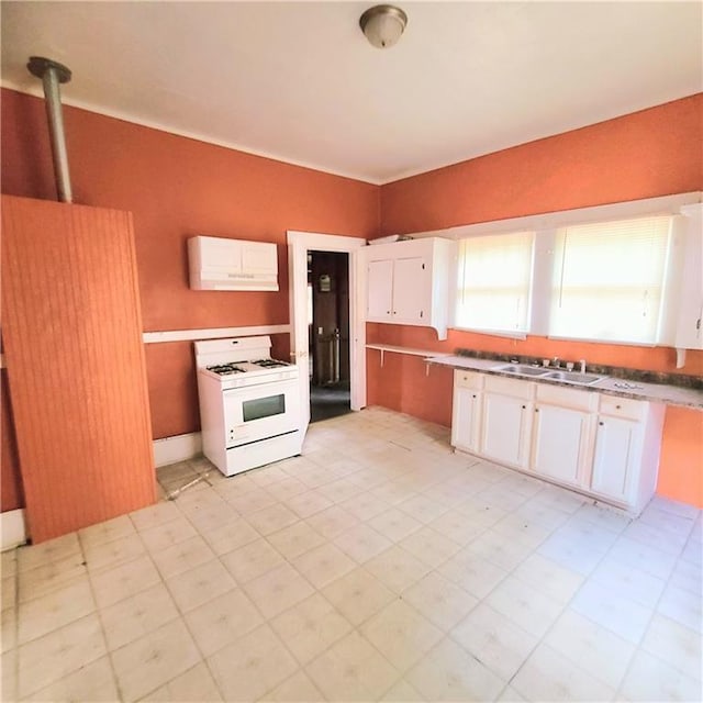 kitchen featuring white gas range, white cabinetry, and sink