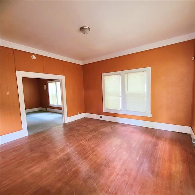 empty room featuring wood-type flooring and ornamental molding