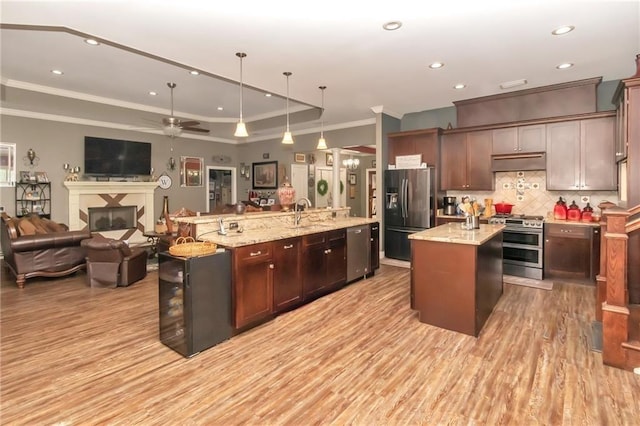 kitchen featuring under cabinet range hood, a large island, refrigerator with ice dispenser, and range with two ovens