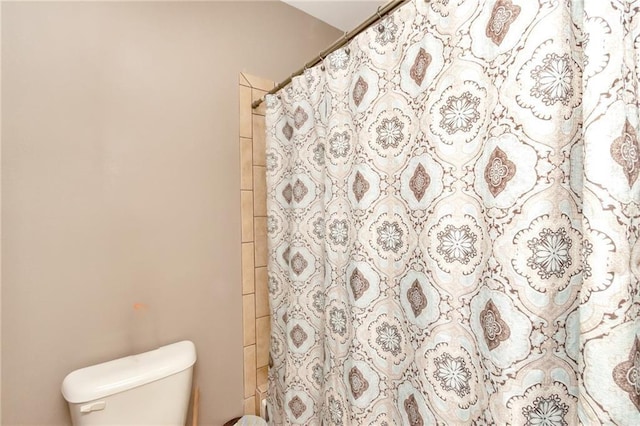 full bath featuring a shower with shower curtain and toilet