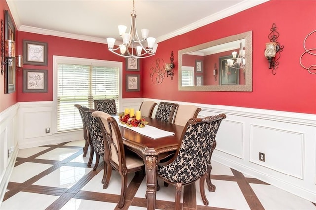 dining area with ornamental molding, wainscoting, a decorative wall, and an inviting chandelier