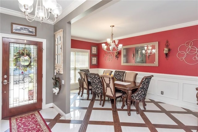 dining room featuring an inviting chandelier, baseboards, crown molding, and a wainscoted wall