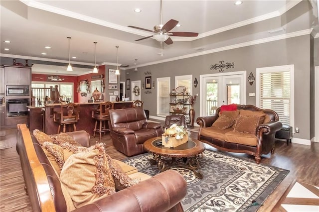 living area featuring french doors, crown molding, a raised ceiling, wood finished floors, and baseboards