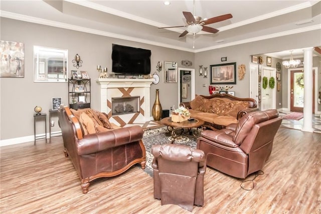 living area featuring a tray ceiling, a fireplace, and decorative columns