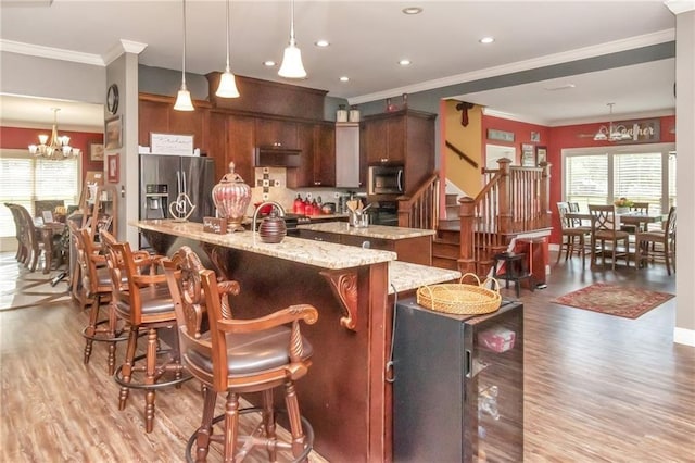 kitchen featuring a chandelier, stainless steel appliances, light wood-style flooring, and a large island with sink