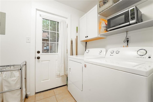 laundry room with washer and clothes dryer, light tile patterned flooring, and cabinets