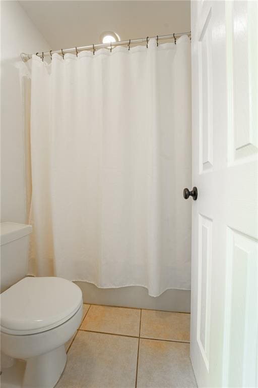 bathroom featuring tile patterned floors, toilet, and walk in shower