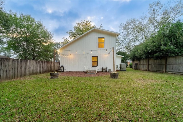 rear view of house featuring a yard and central air condition unit